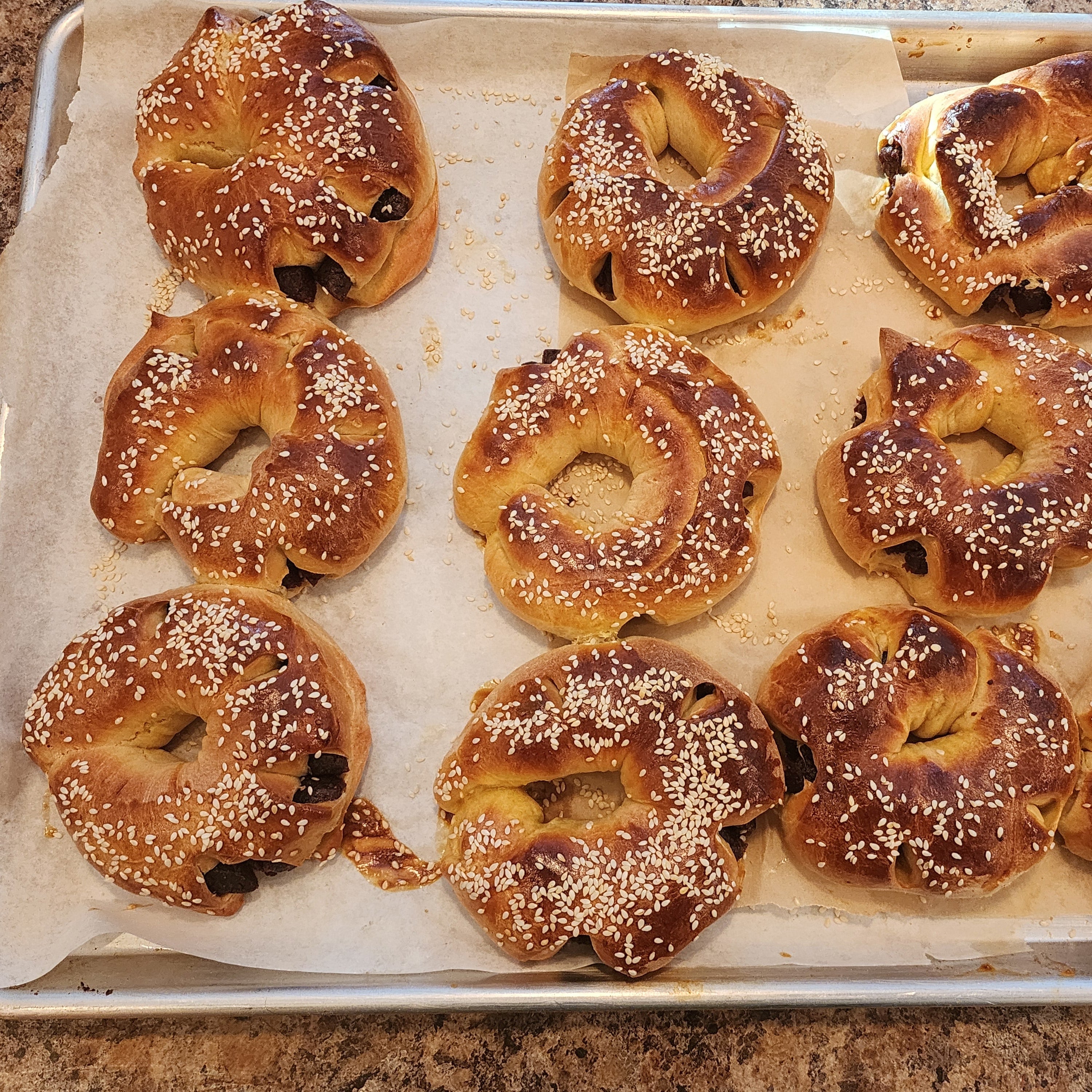 Baked date breads with sesame seeds on a baking tray