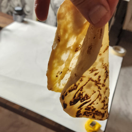 Hand holding a piece of flat bread over a marble countertop.
